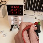 Ein Labrnetzteil welches 1,2V und 0,101A anzeigt. Im Vordergrund eine Hand welche eine Messspitze auf dem Pluspol eines AA Akkus hält