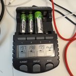 Ein Ladegerät mit zwei AAA und einem AA Akku. Im Deisplay kann man sehen das alles Akkus mit fast 200mA geladen werden. Um das Gerät liegen Kabel