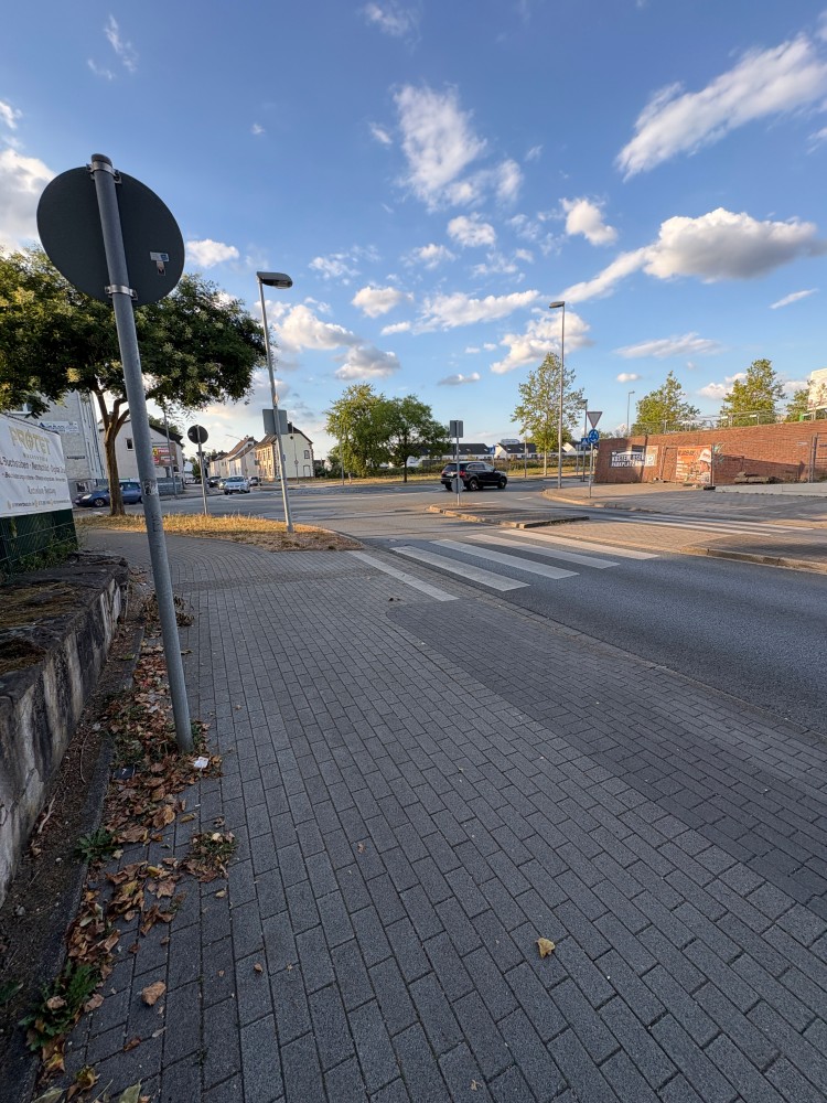 Der Kreisverkehr aus einer anderen anderen Perspektive aufgenommen. Im Vordergrund ist eine Zebrastreifen zu erkenn im Hintergrund sieht man einen blauen Himmel